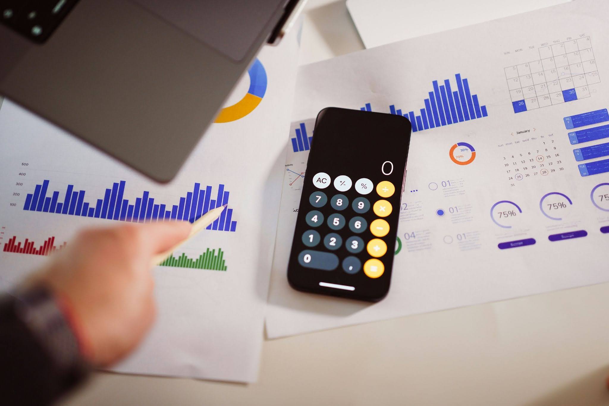 Calculator on a desk next to a stack of charts