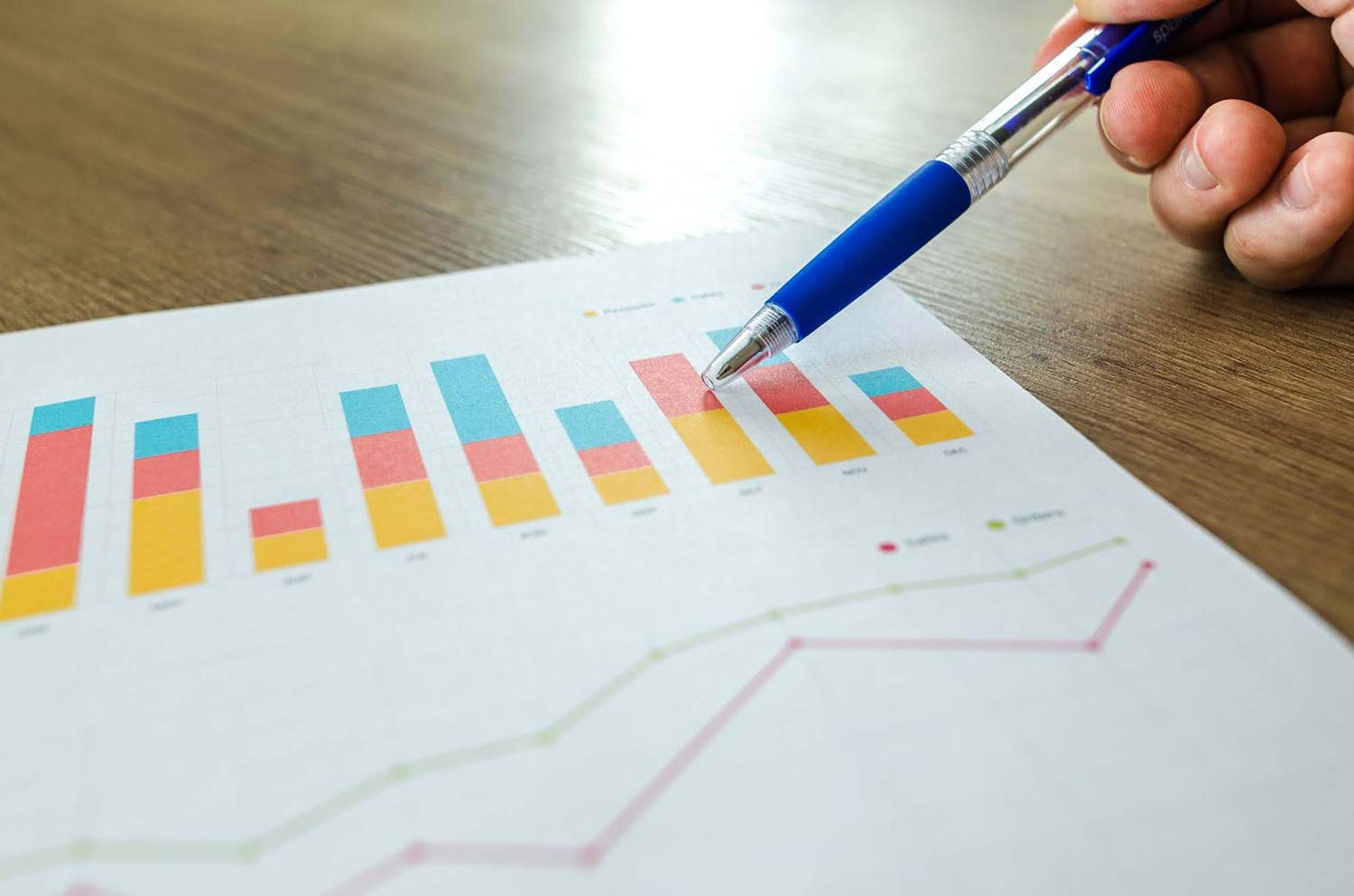 A person using a pen to point out metrics on a chart