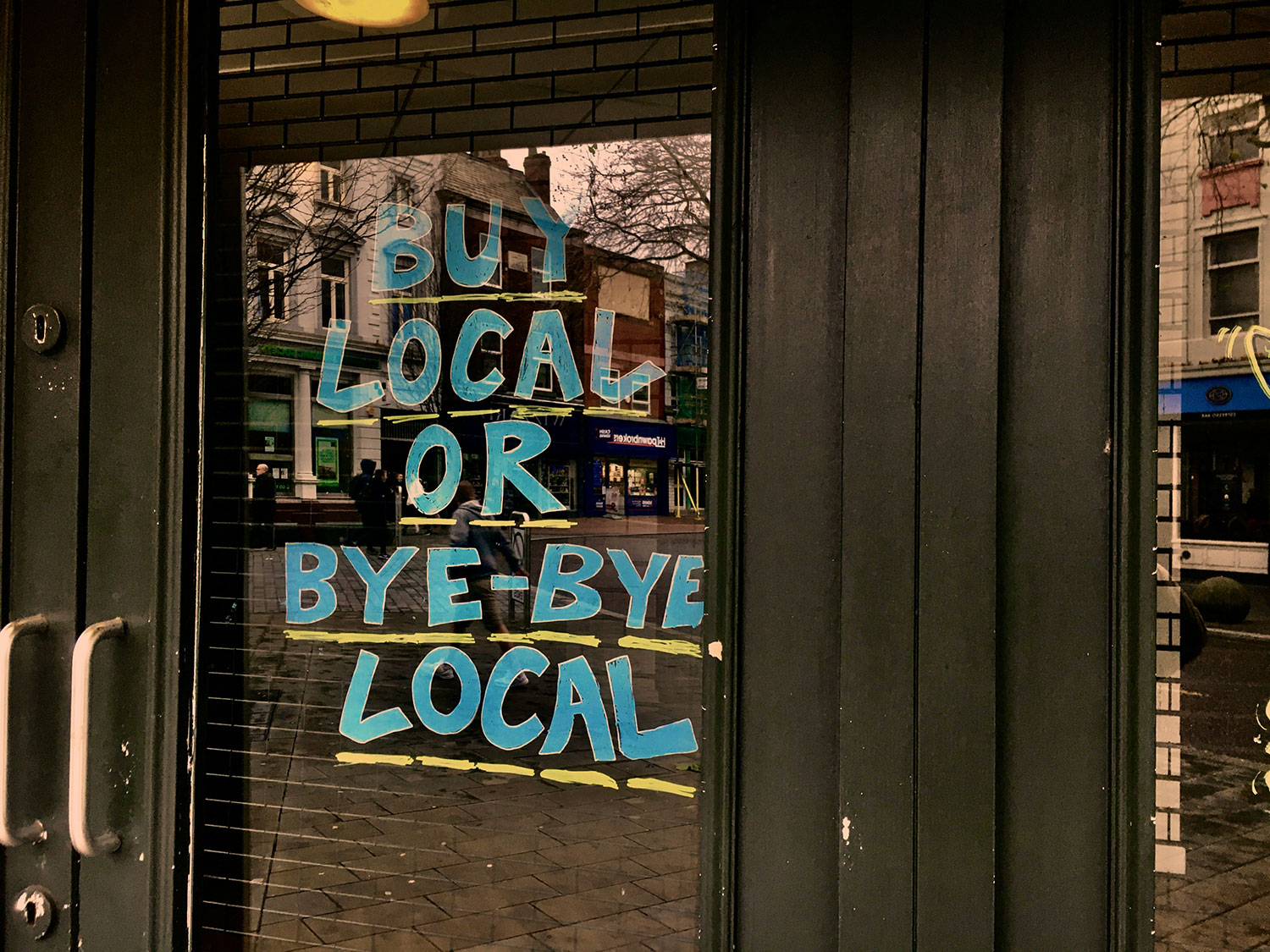 The door for a business with "Buy Local or Bye-Bye Local" on it